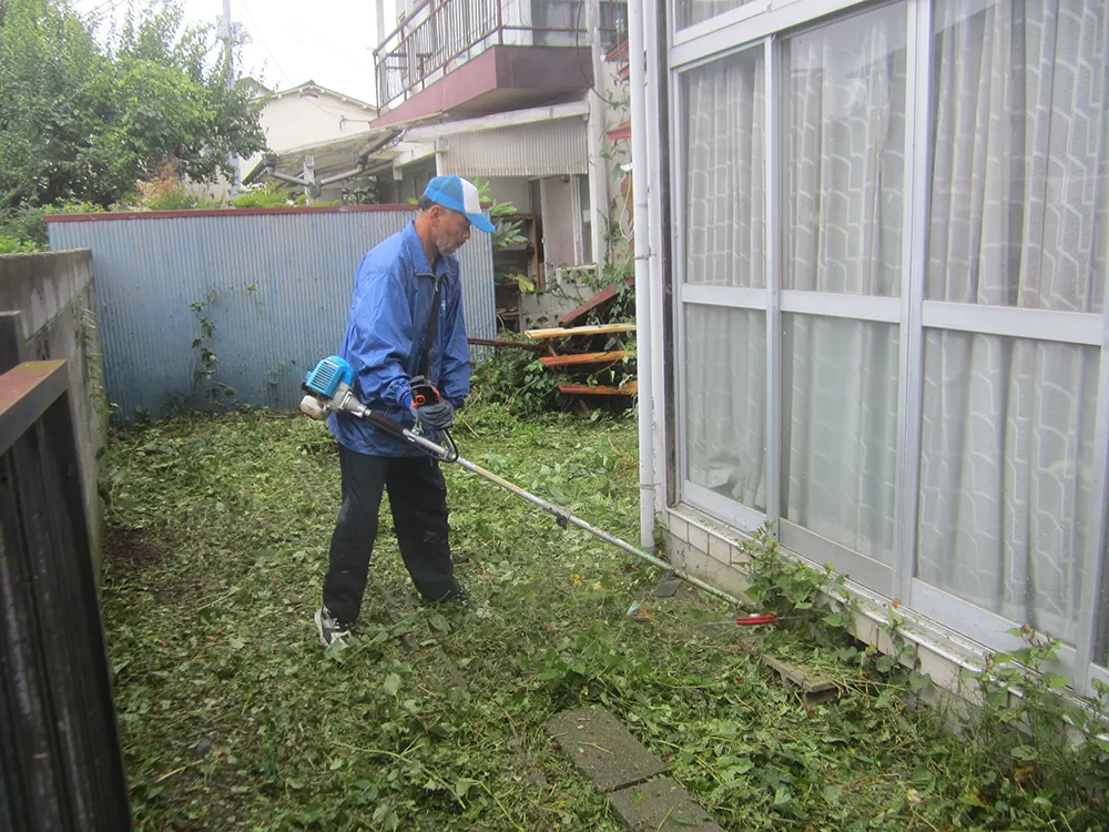 庭で草刈りをする作業員